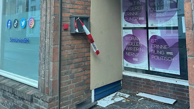 Deutschland: die mit Sperrholz abgedeckte zerstörte Tür nach dem Angriff auf die Geschäftsstelle der Sinti-Union Schleswig-Holstein. Daneben die auf den Holocaust verweisenden Plakate. (Foto: Sinti-Union SH)